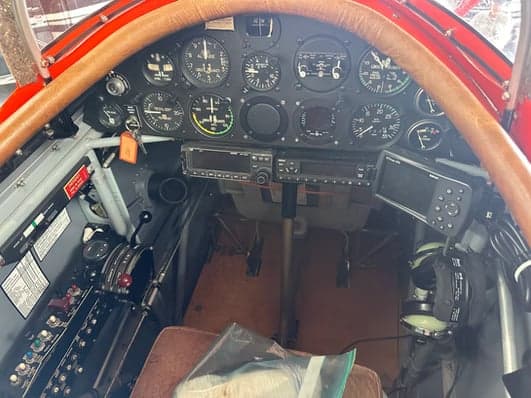 An orange biplane parked in a hangar.