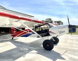 A white and red aircraft is parked on the tarmac with a shark mouth design.
