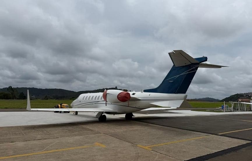 Rear side view of a white Learjet with blue tail on the tarmac.