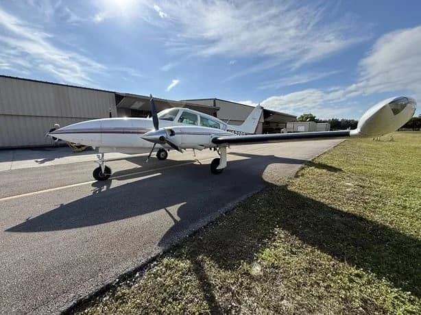 Side view of a white twin-engine aircraft with N87393 on the tail, parked on an airfield.