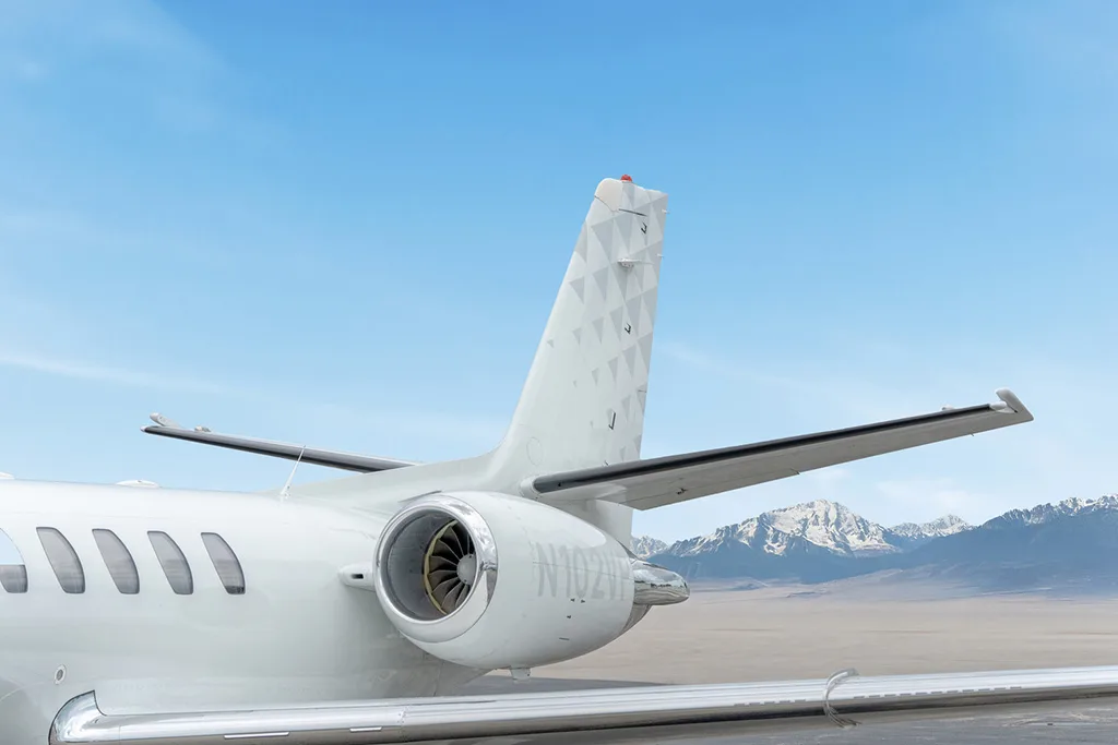 A close-up of the vertical stabilizer and engine of a white Cessna Citation CJ3 (N102VP) against a blue sky.