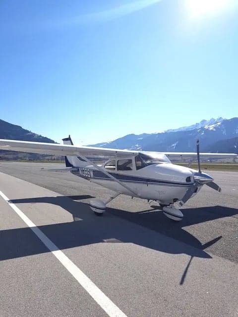 Cessna 182 Skylane, tail number N138SW, parked on the tarmac with mountains in the background.