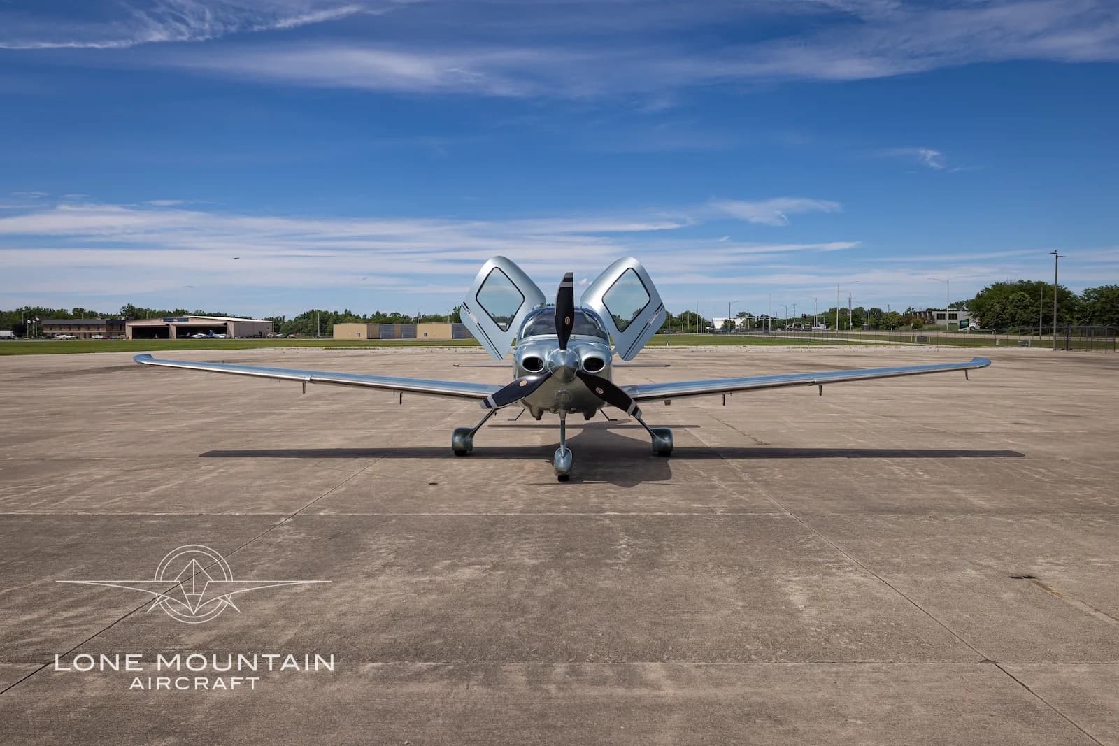 A front view of a silver Cirrus SR22 aircraft (N234PY) with its doors open, parked on a tarmac.