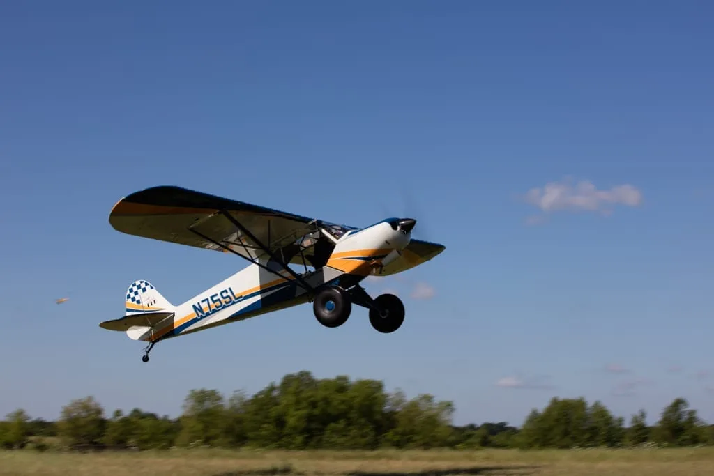 Aircraft taking off from a grassy field.