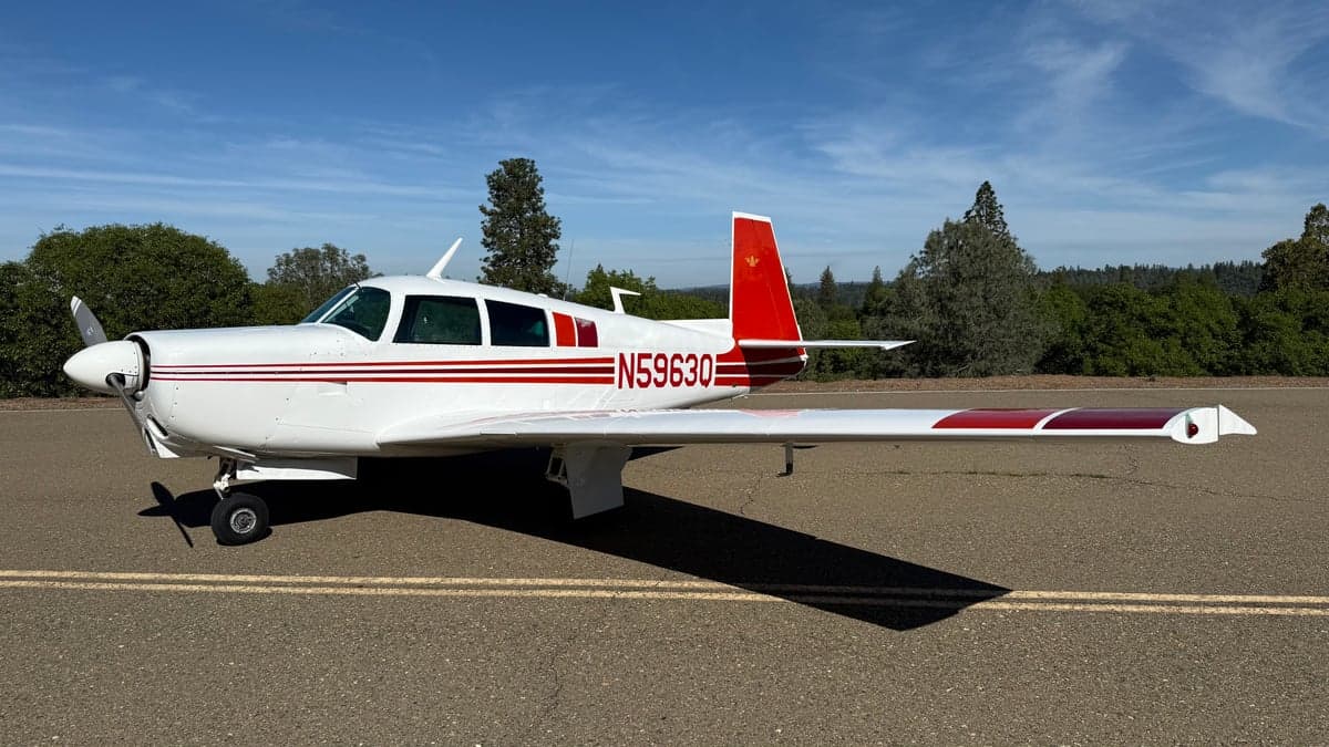 A Mooney aircraft with a white and red paint scheme on the tarmac.