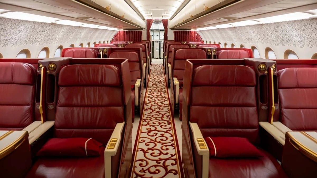 A view down the aisle of a private jet with red leather seats.