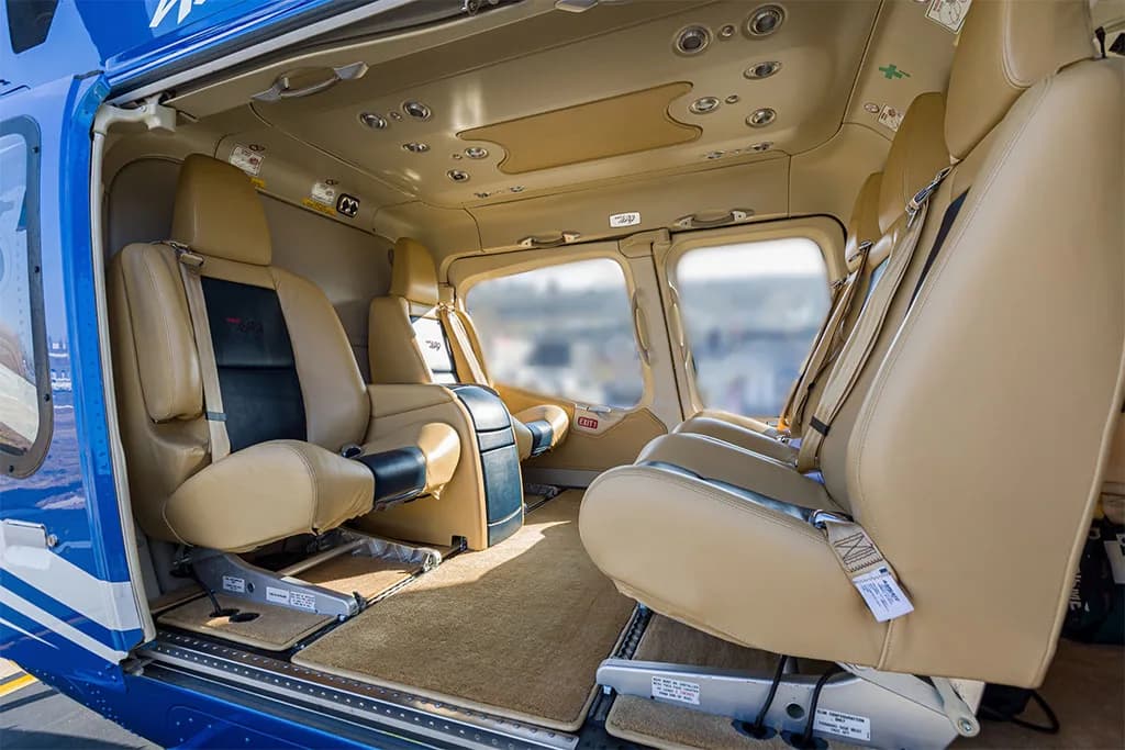 The tan leather interior cabin of the helicopter with multiple passenger seats.
