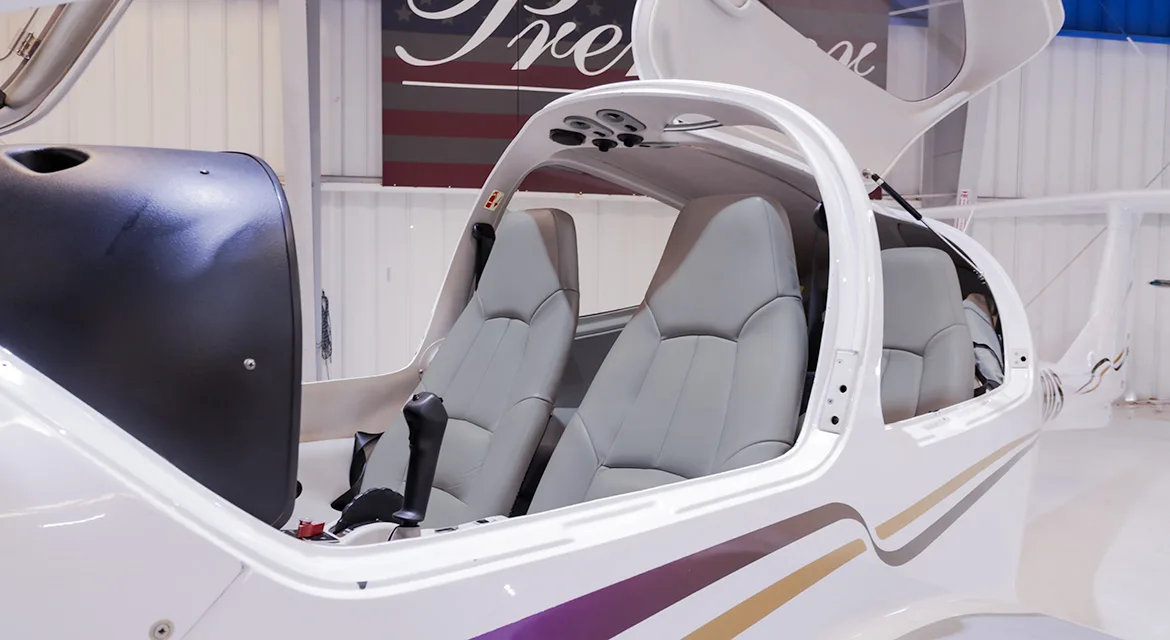 The light gray leather interior seats of a Diamond DA40 Star aircraft with the canopy open.
