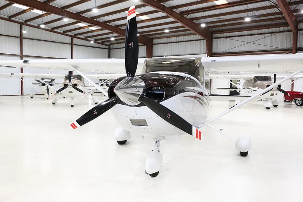 A white and brown Cessna Skylane N788RM is parked in a hangar, viewed from the front.
