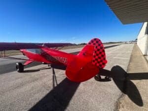 A red aircraft with a checkered tail is parked on the tarmac.