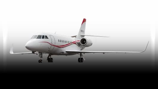 A white Dassault Falcon 900EX business jet with red accent stripes and a red tail, seen from the front-side on a white background.