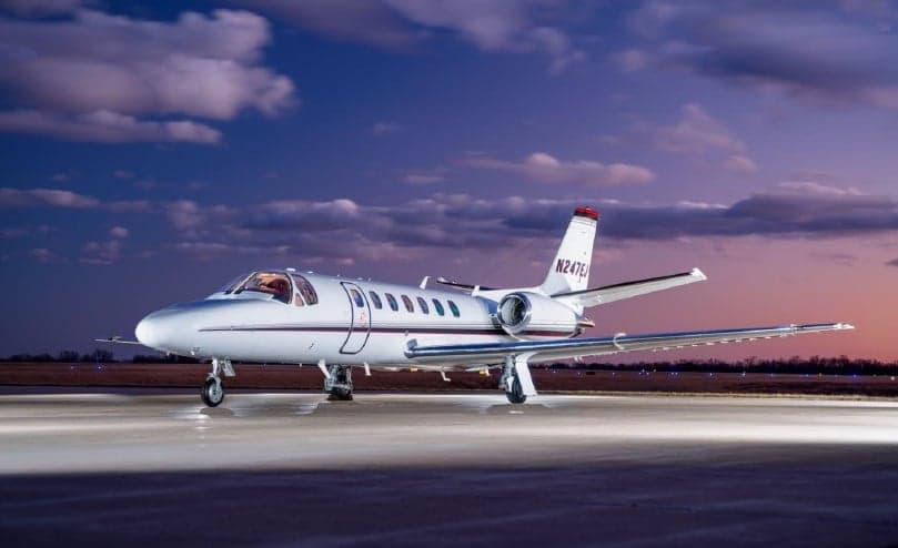 A Cessna Citation CJ3 sits on the tarmac at sunset.