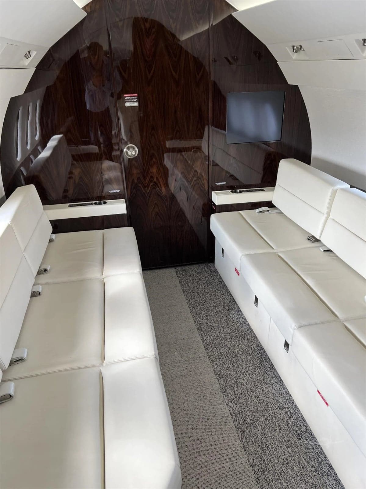 Interior view of the aircraft cabin with cream-colored leather seats and a passenger.