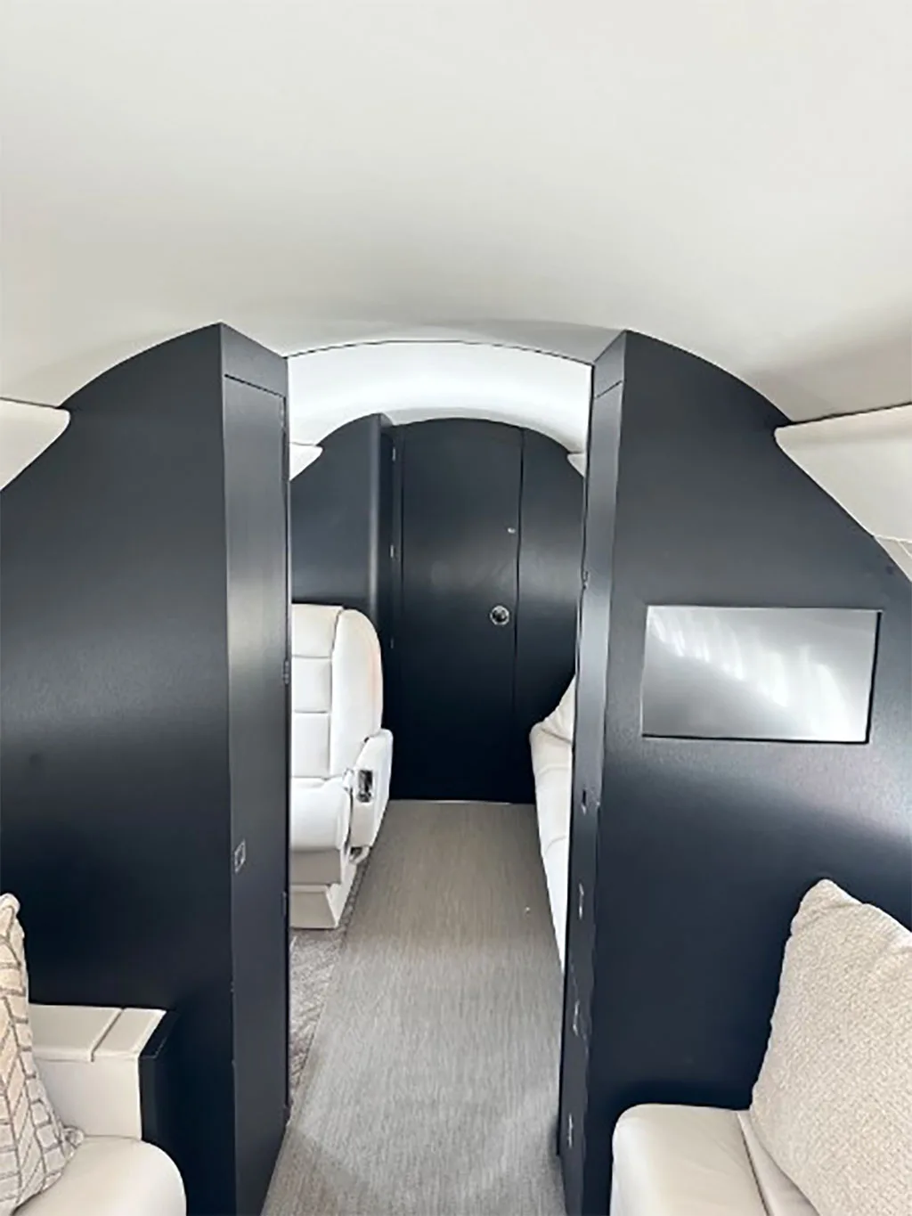 A view down the aircraft cabin aisle, showing dark cabinetry and the rear section of the luxurious interior.