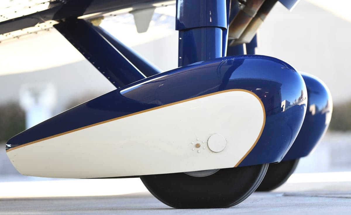 Close-up of the landing gear of a blue and white biplane.
