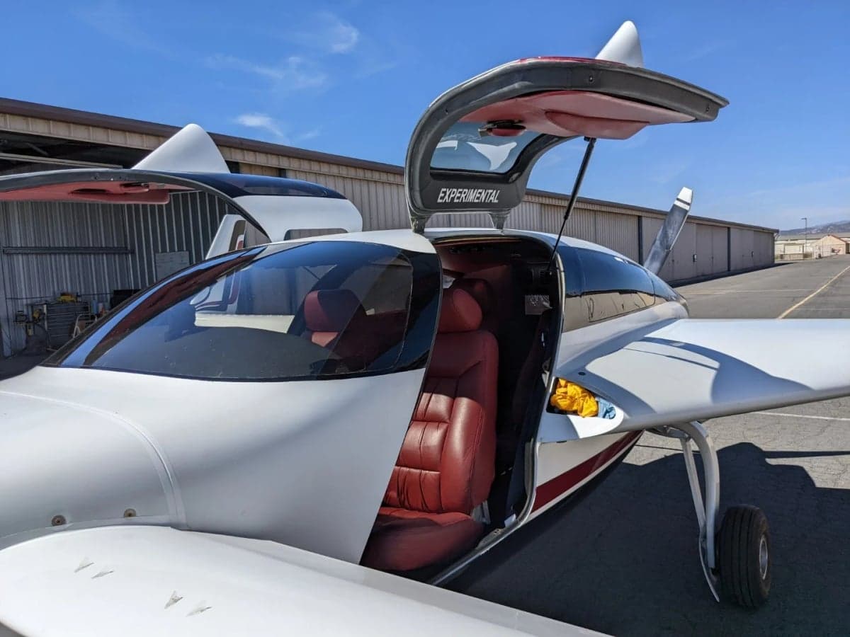 Close-up of N7779X aircraft with gull-wing doors open, showing the interior.