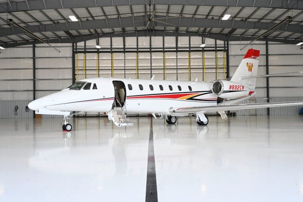 A Citation Sovereign aircraft with tail number N892CW is parked in a hangar with the door open.
