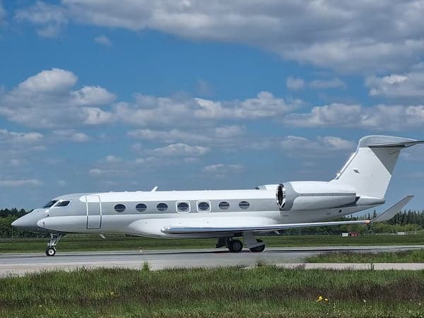 A Gulfstream G550 aircraft is parked on the tarmac under a cloudy sky.