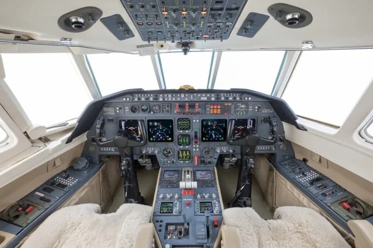 The modern cockpit of a private jet with multiple digital displays and controls.