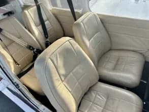 The interior of a Piper PA-28 Cherokee, showing the cream-colored leather seats.