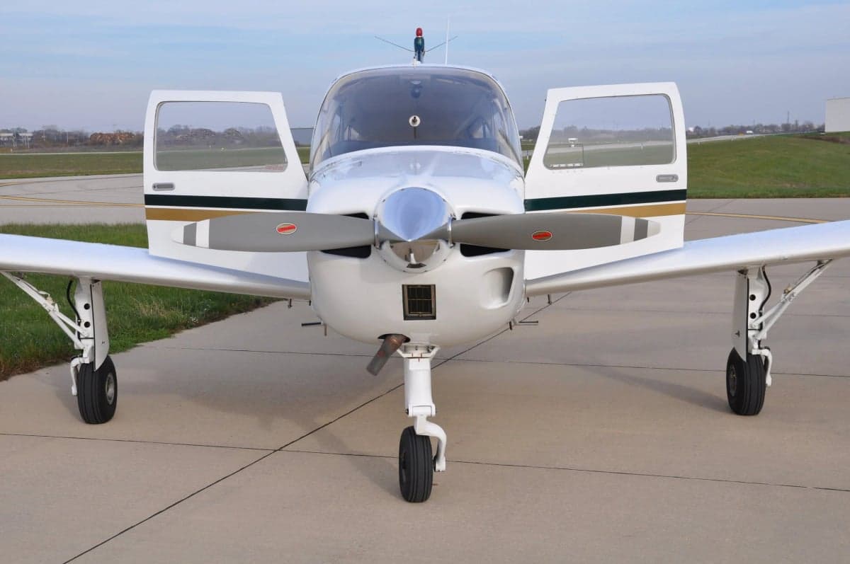 Front view of a white and gold aircraft with open doors on the tarmac.