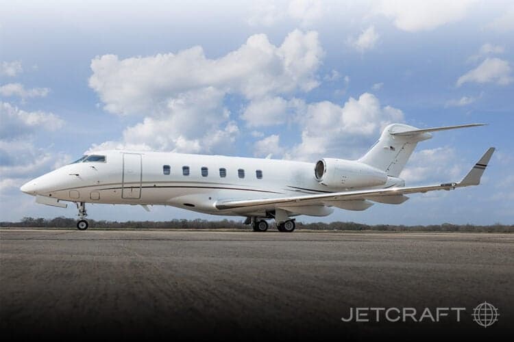 Side view of a white Bombardier Challenger 300 on the tarmac.