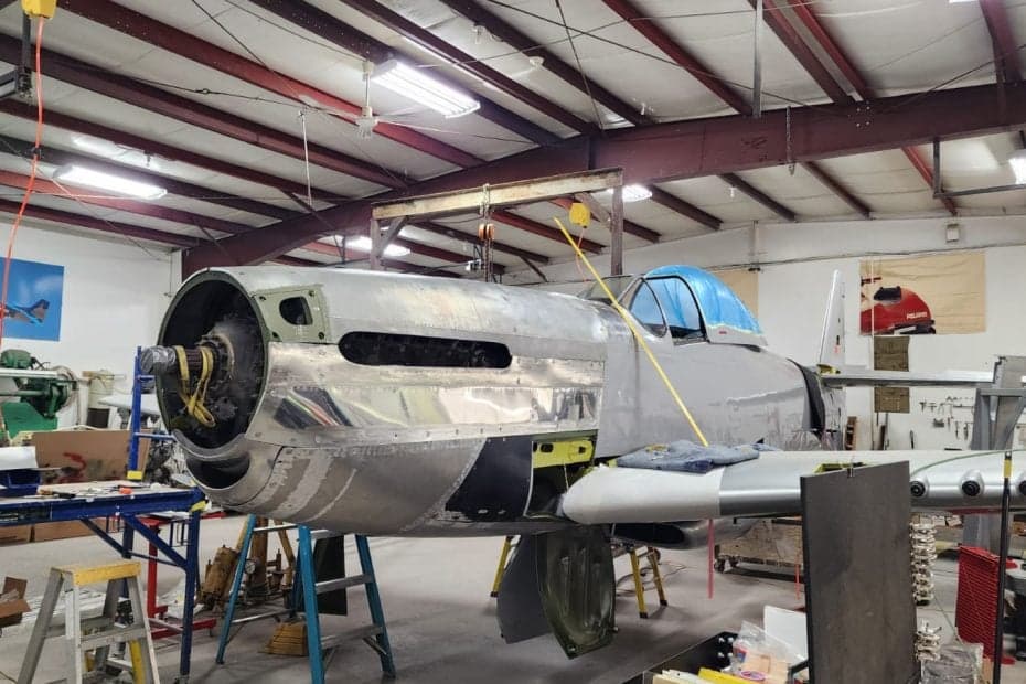 A P-51 Mustang is undergoing restoration in a hangar.