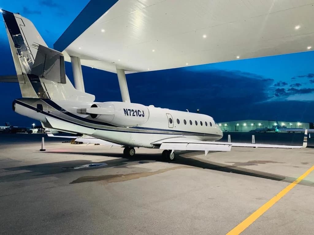 A Falcon jet parked on the tarmac at dusk.