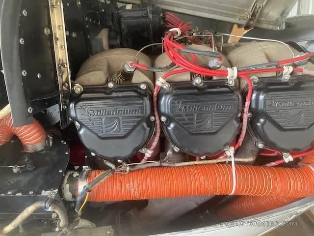 A close-up view of an aircraft engine's cylinder heads with "Millennium" branding and red ignition wires.