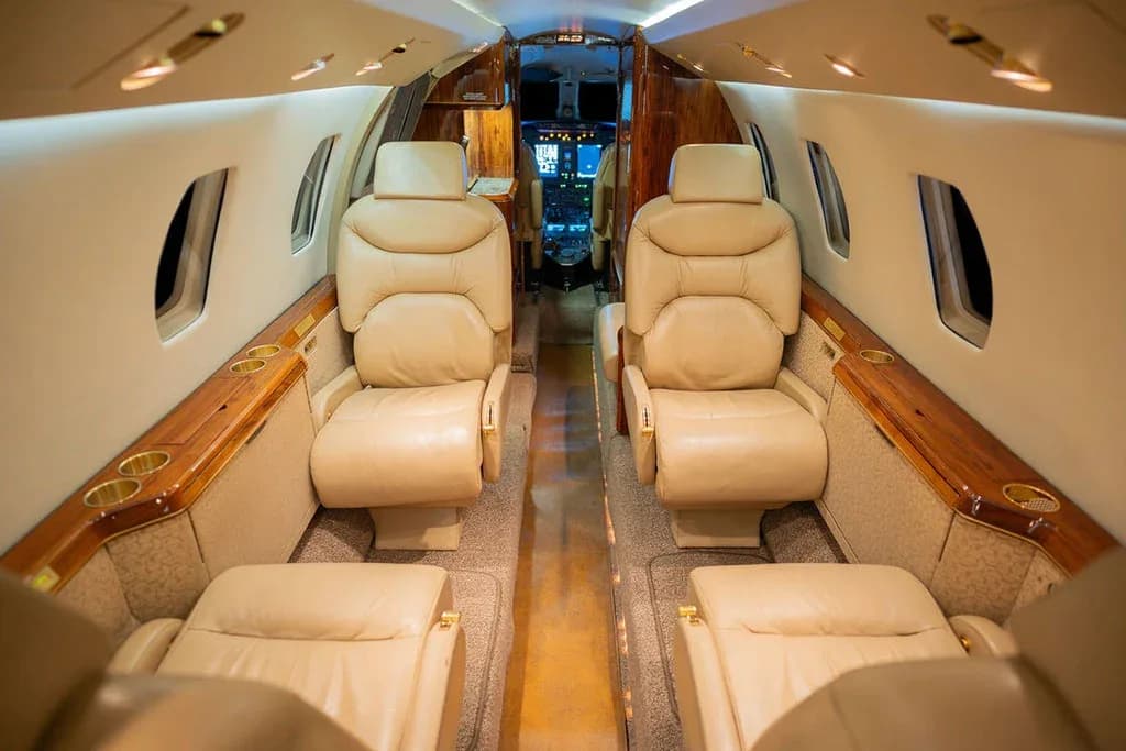 The aircraft's interior cabin with beige leather seats and polished wood trim.