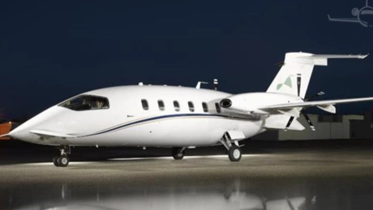 A Piaggio Avanti aircraft is parked on the tarmac at night.