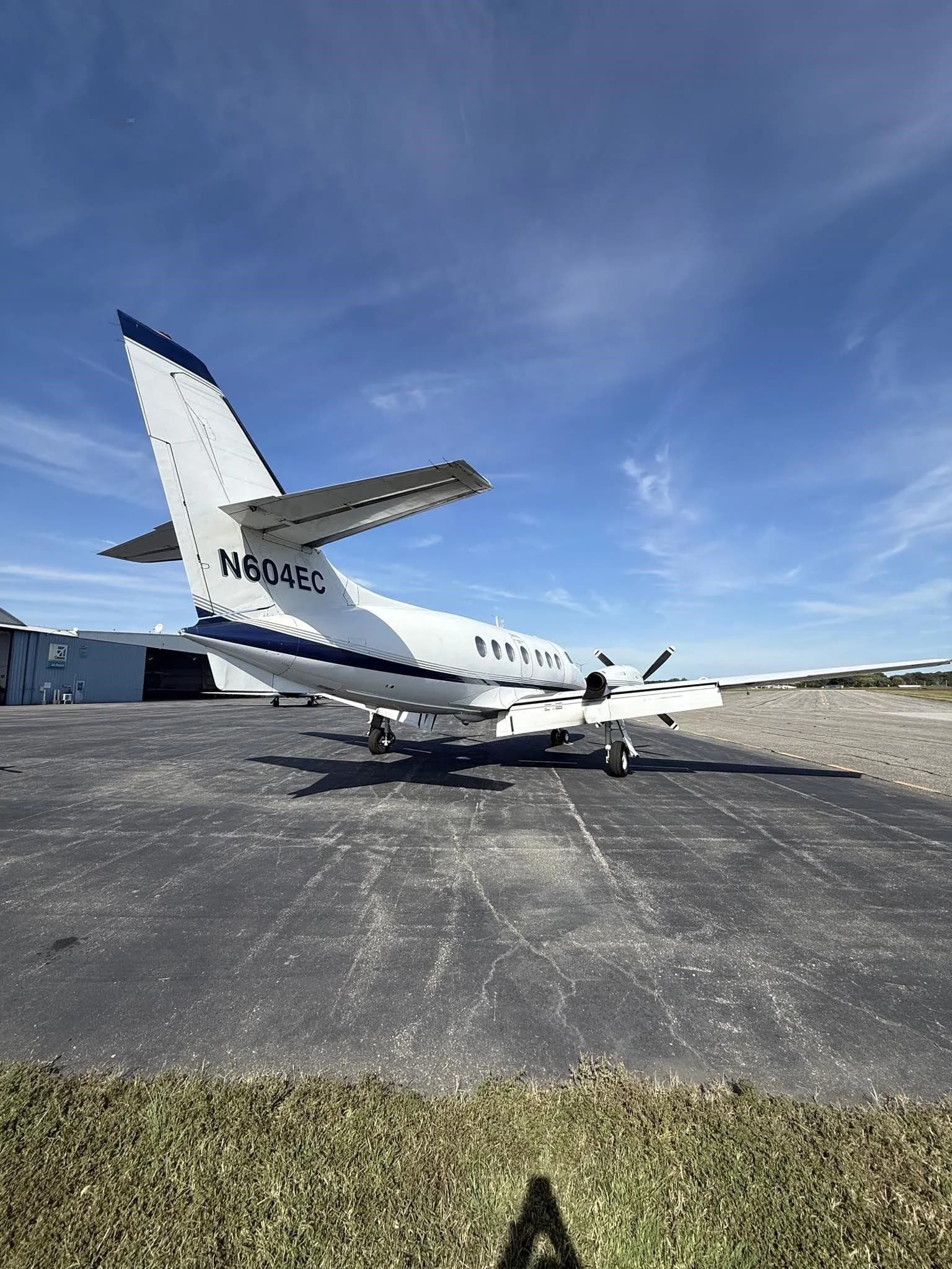 A rear-quarter view of a white Jetstream 31 aircraft with blue accents, tail number N604EC, parked on an asphalt tarmac.