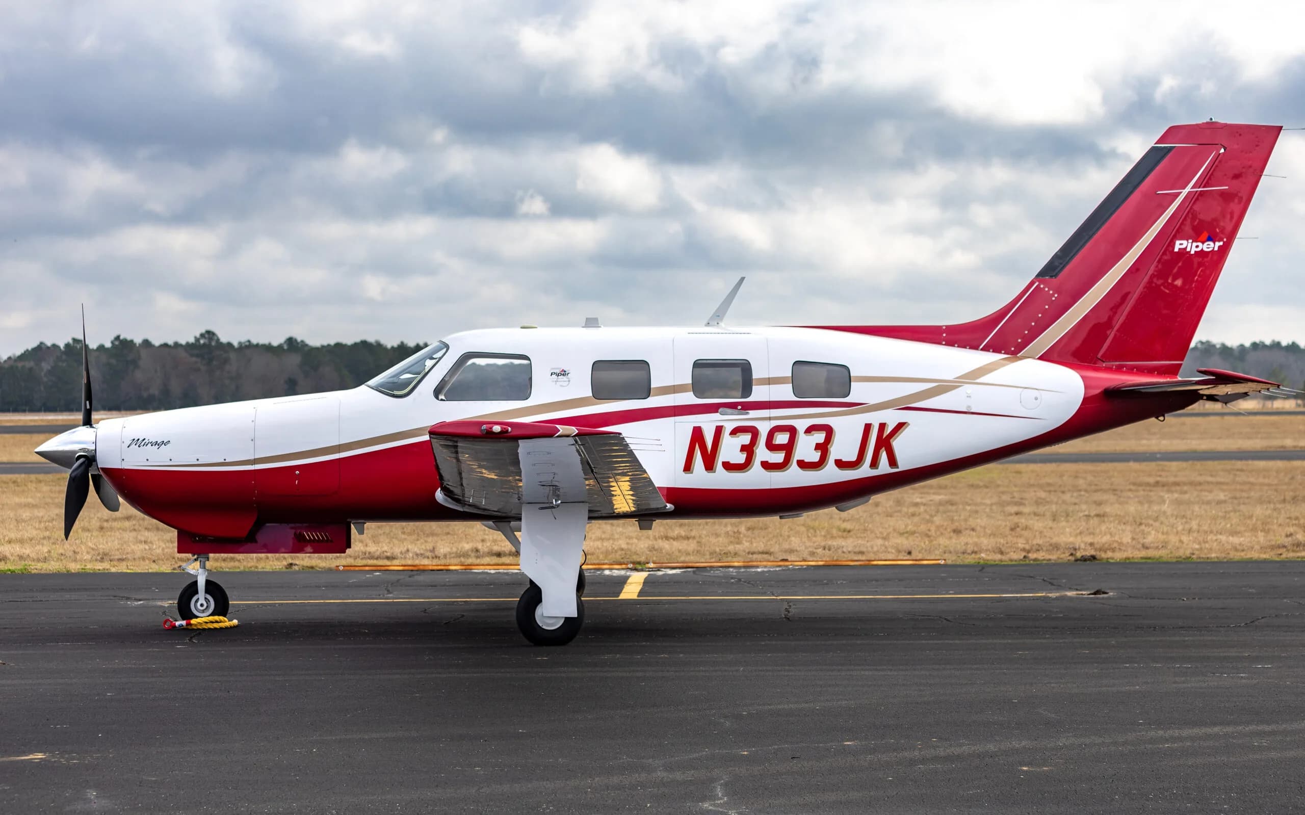 Side view of the Piper Mirage N393JK on the tarmac.