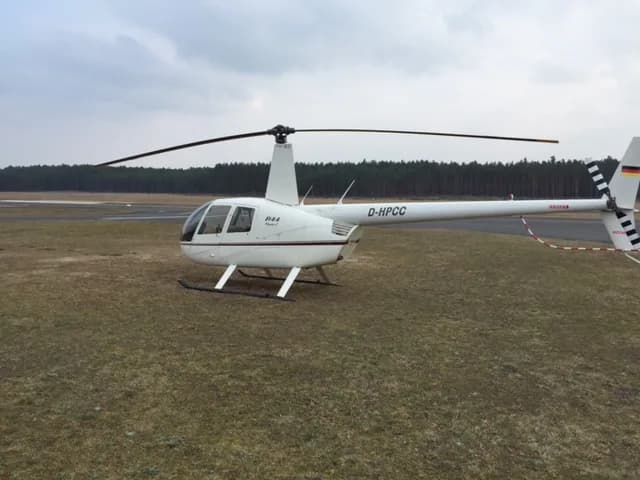 Robinson R44 helicopter on the ground at an airfield.