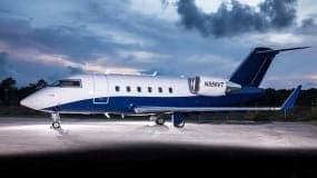Side view of a Challenger aircraft with a blue and white paint scheme at dusk.