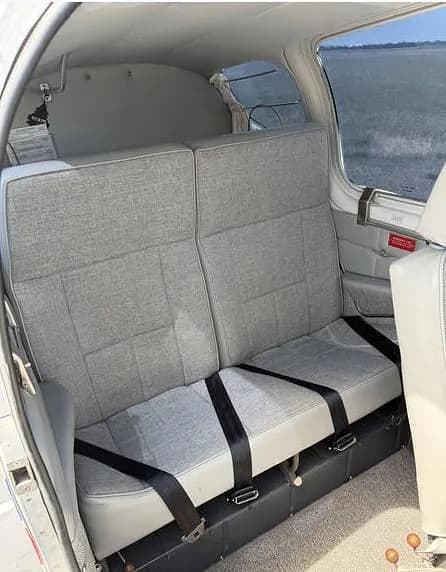 The aircraft's rear cabin with two grey fabric seats and black seatbelts.