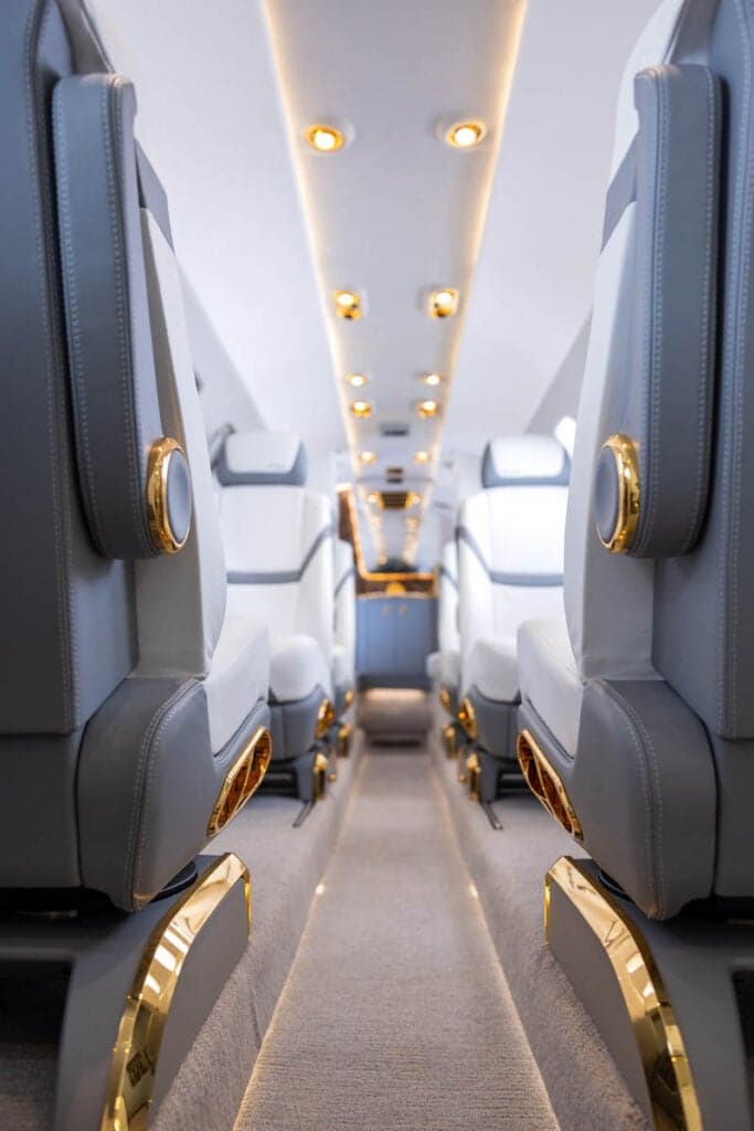 A view of the Citation CJ3 cabin interior with white leather seats and gold trim.