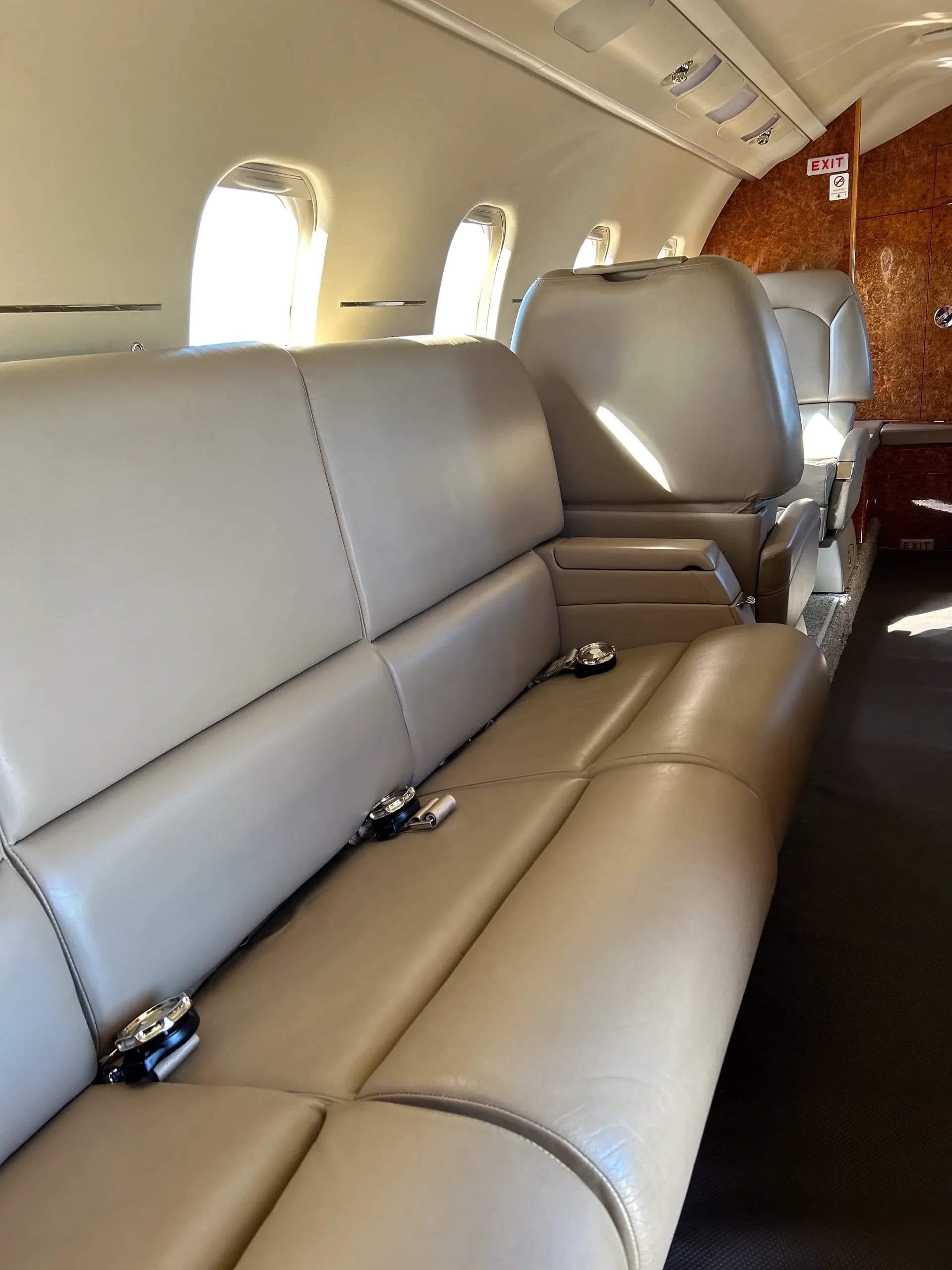 A small beige seating area with wood paneling next to an aircraft door and window.