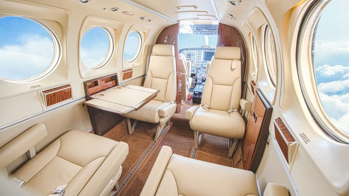 Aircraft interior with leather seats and a table.