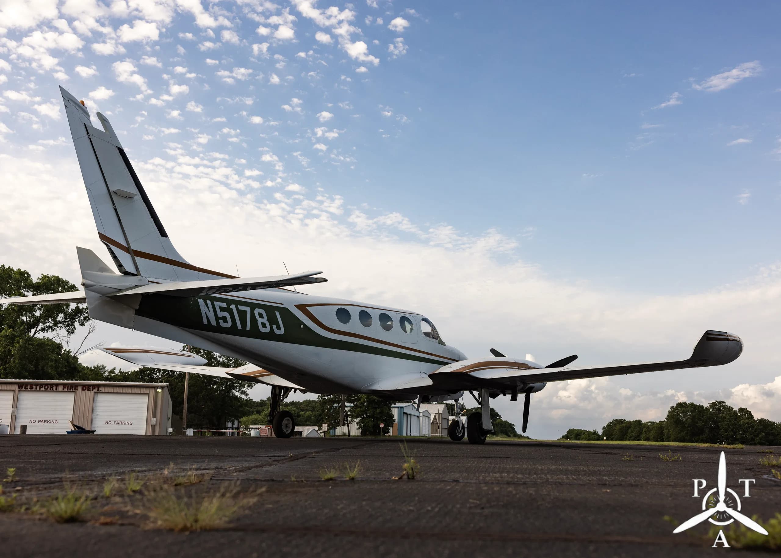 A low-angle side view of a white and green Cessna 340A twin-engine aircraft, N5178J, parked on an asphalt ramp.