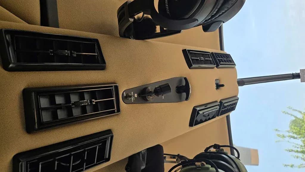 An overhead view of a helicopter's tan interior panel shows air vents and toggle switches.