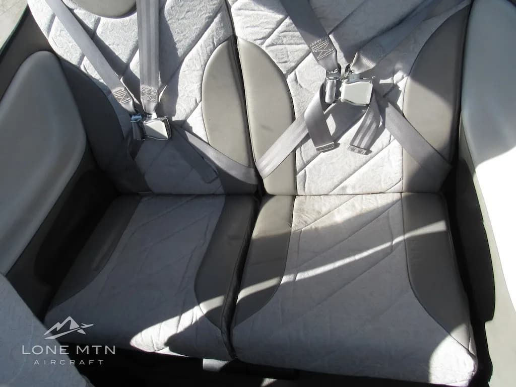 The two rear passenger seats of the aircraft, upholstered in grey fabric and leather, with seatbelts fastened.