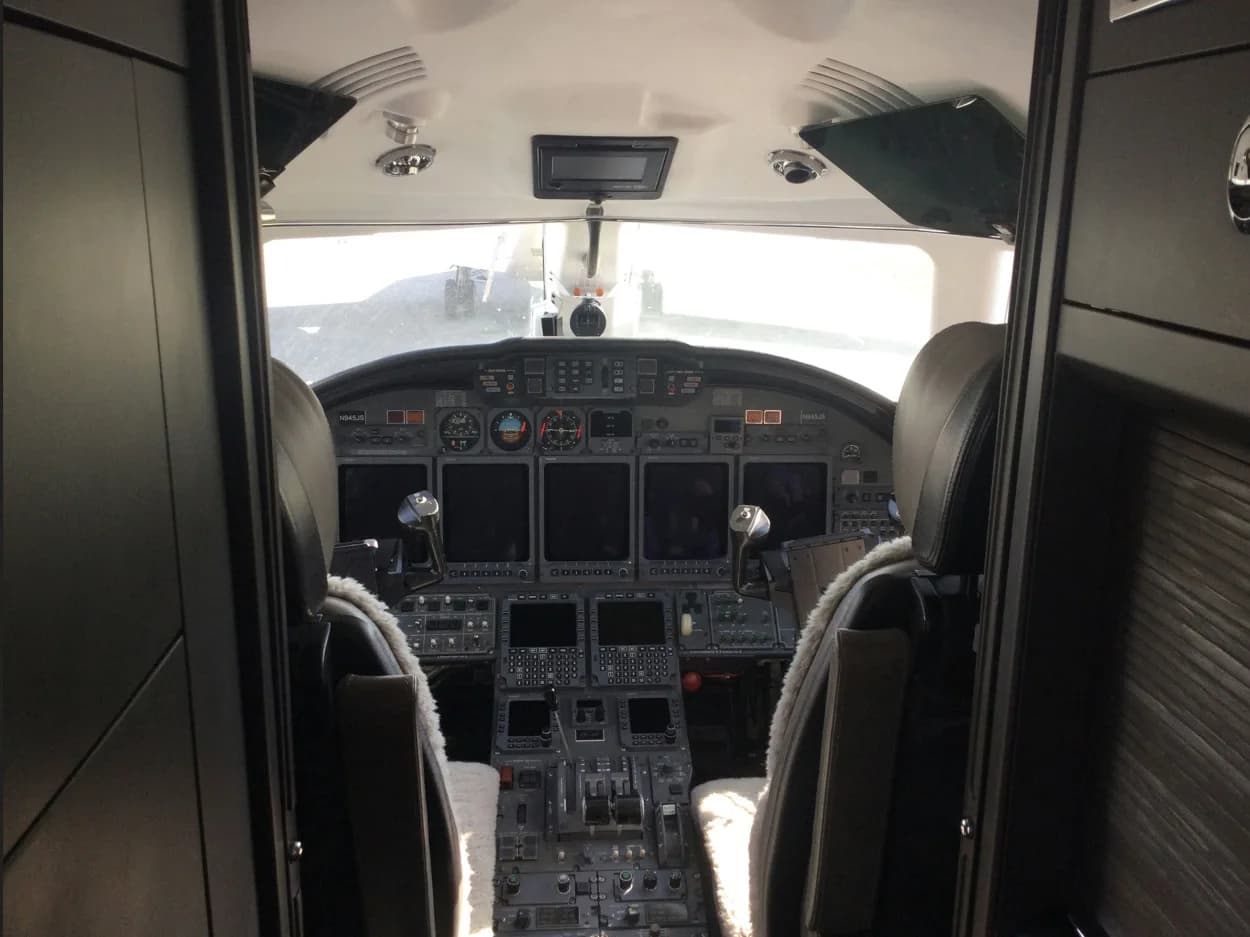 Aircraft cockpit instrument panel with multiple displays and controls, viewed from the cabin.
