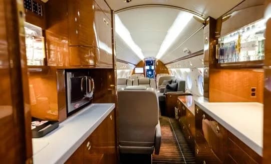 Interior of a private jet with a galley and seating area.