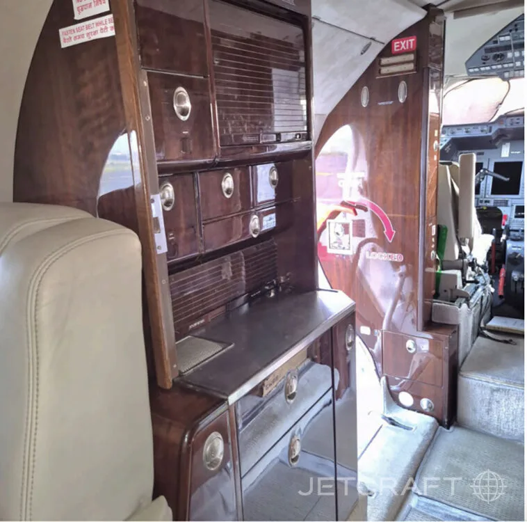A view of the galley and storage cabinetry inside a business jet cabin, looking towards the cockpit.