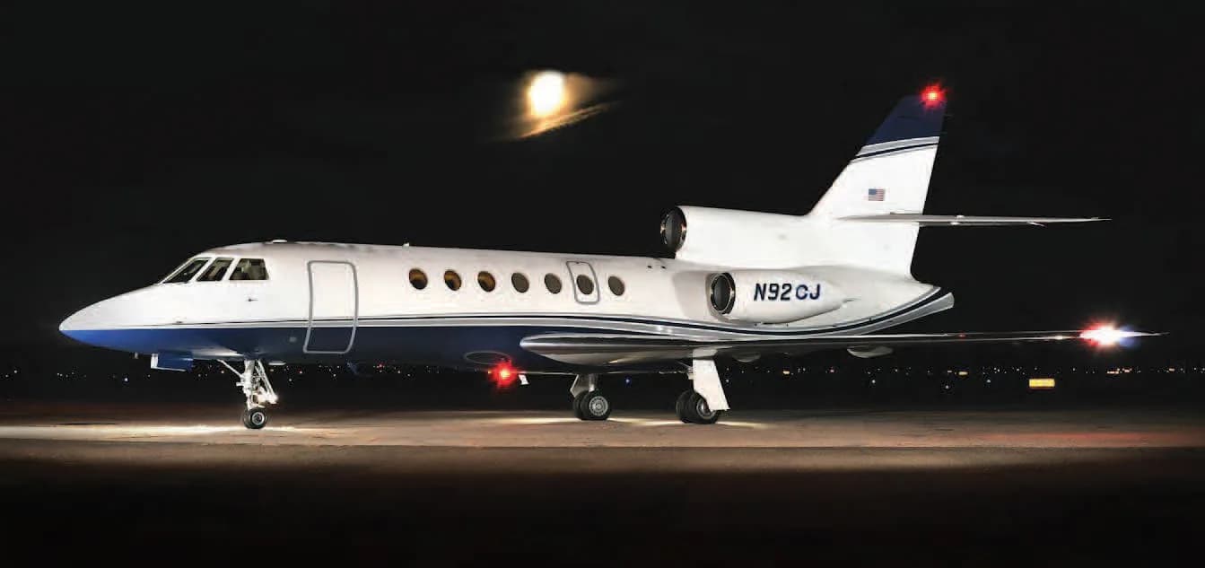 Side view of the aircraft N92CJ on the tarmac at night.