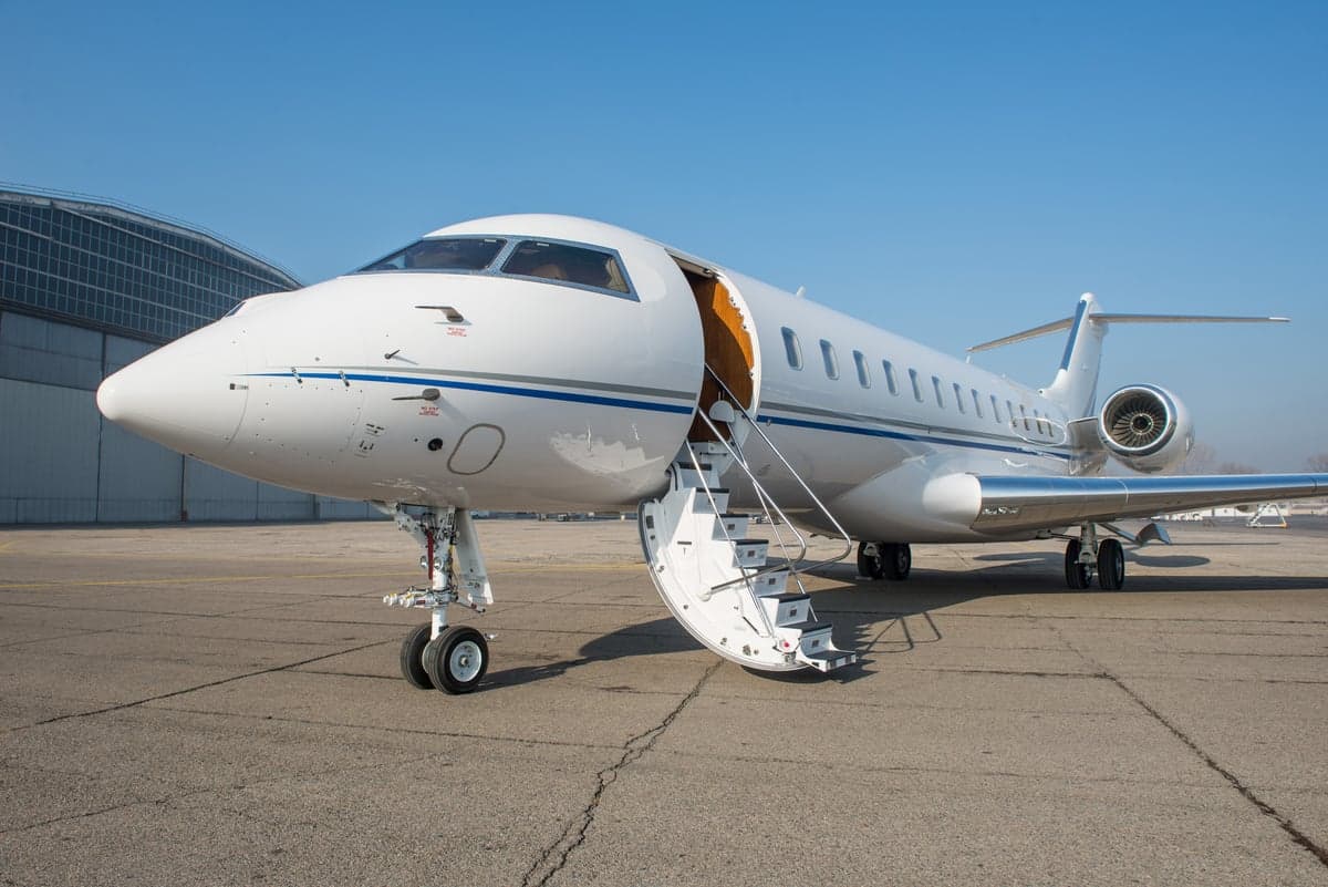 A white private jet with an open door and stairs extended.