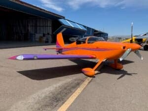 An orange and purple aircraft parked on the tarmac.