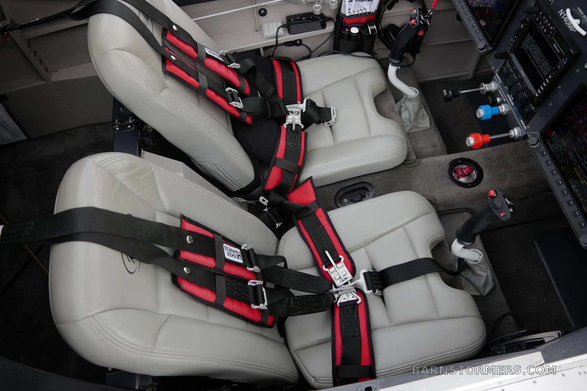 The gray leather seats with red and black harnesses in the cabin of a Vans RV-140MP aircraft.