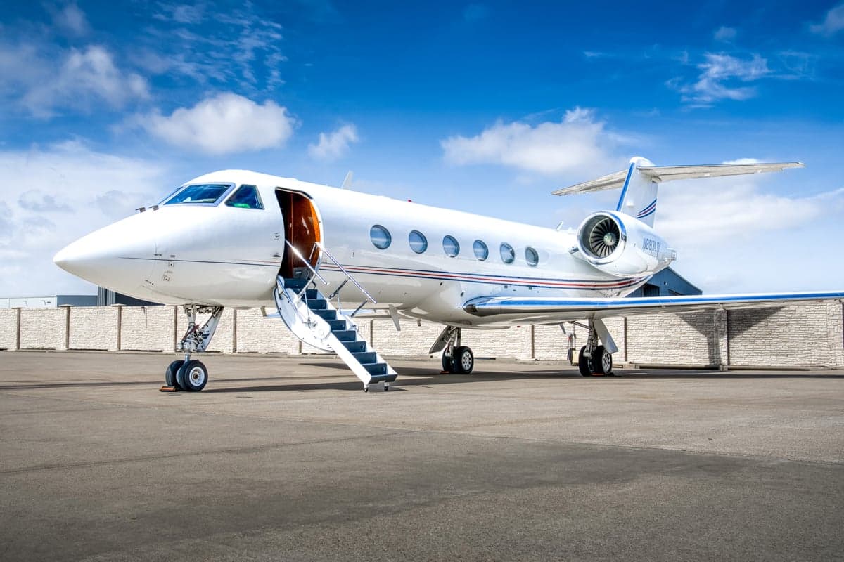 A Gulfstream G450 aircraft is parked on the tarmac with the airstair door open.